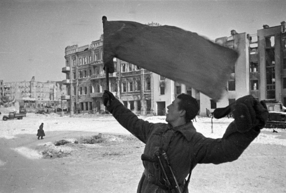 Боец держит развевающийся флаг на улице Сталинграда (Фото 31.01.1943 года). ©РИА Новости